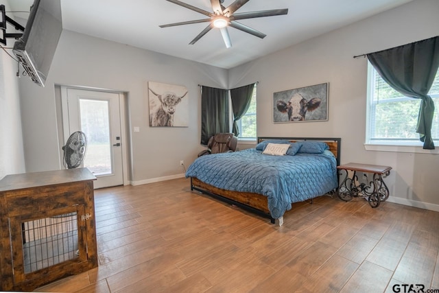 bedroom featuring light hardwood / wood-style floors, ceiling fan, multiple windows, and access to outside