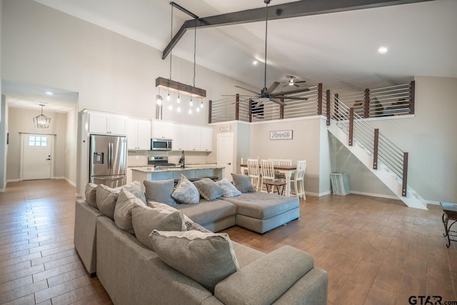 living room featuring high vaulted ceiling, beamed ceiling, ceiling fan, and light wood-type flooring