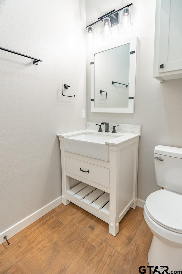 bathroom featuring wood-type flooring, toilet, and vanity