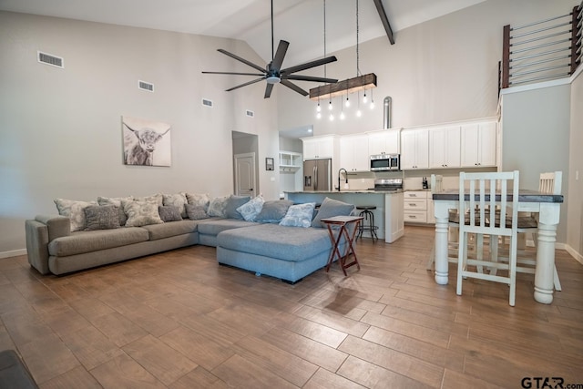 living room featuring ceiling fan, wood-type flooring, sink, and high vaulted ceiling