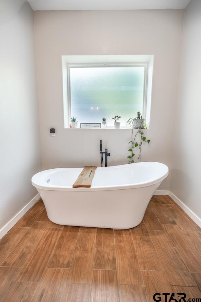 bathroom featuring hardwood / wood-style floors and a tub to relax in