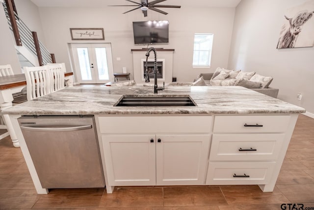 kitchen with white cabinets, sink, stainless steel dishwasher, ceiling fan, and light stone countertops