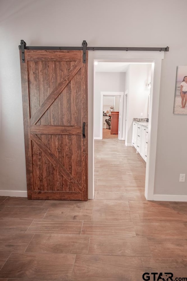 hall featuring light wood-type flooring and a barn door