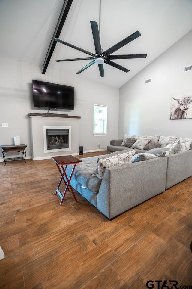 living room featuring hardwood / wood-style floors, ceiling fan, and vaulted ceiling with beams