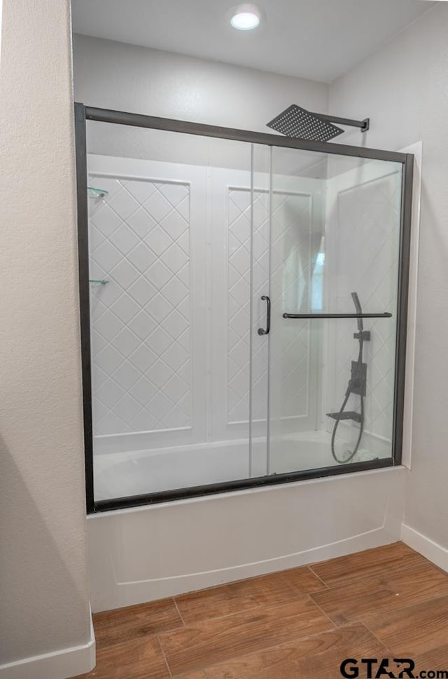 bathroom featuring hardwood / wood-style floors and combined bath / shower with glass door