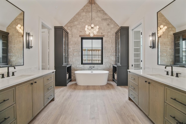 3312 Forest Ct, Tyler, TX 75703 - bathroom with a chandelier, two vanities, vaulted ceiling, wood finished floors, and a freestanding tub