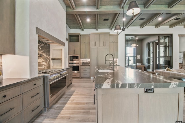 3312 Forest Ct, Tyler, TX 75703 - kitchen with appliances with stainless steel finishes, light wood finished floors, a spacious island, tasteful backsplash, and a sink