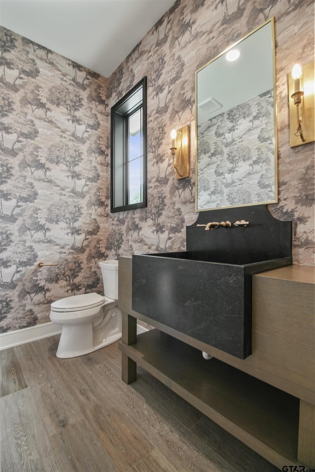 3312 Forest Ct, Tyler, TX 75703 - bathroom with wood finished floors, toilet, baseboards, wallpapered walls, and vanity
