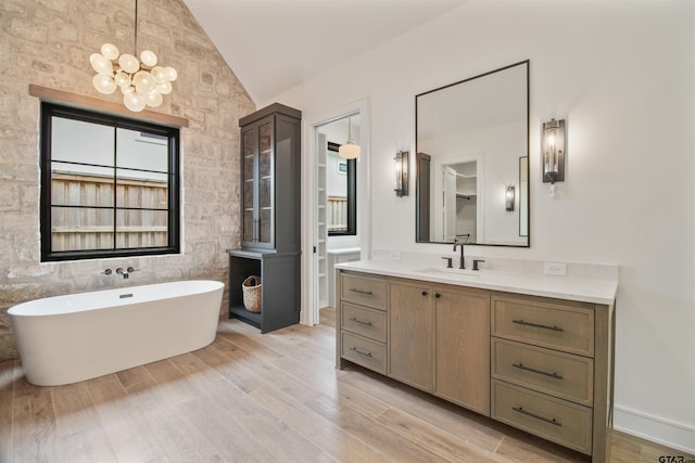 3312 Forest Ct, Tyler, TX 75703 - full bathroom with lofted ceiling, a freestanding tub, vanity, wood finished floors, and a chandelier