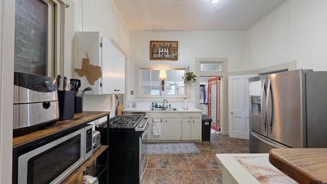 kitchen featuring white cabinets, stainless steel refrigerator with ice dispenser, sink, and a high ceiling