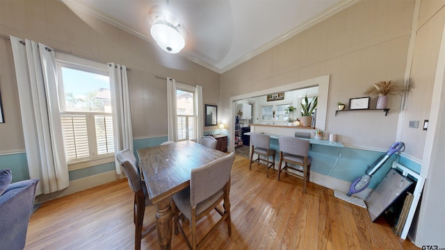 dining room with light hardwood / wood-style flooring, crown molding, and vaulted ceiling