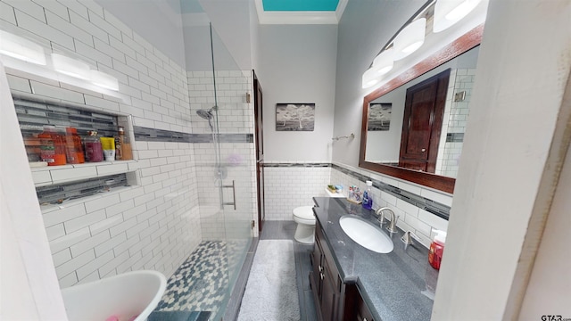 bathroom with vanity, toilet, an enclosed shower, and tile walls