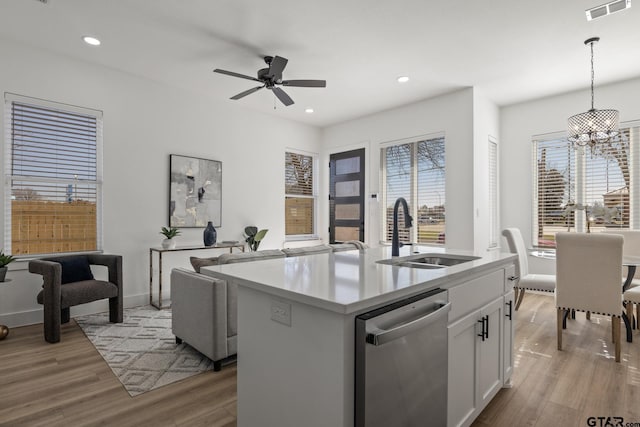 kitchen with sink, white cabinetry, hanging light fixtures, stainless steel dishwasher, and a kitchen island with sink