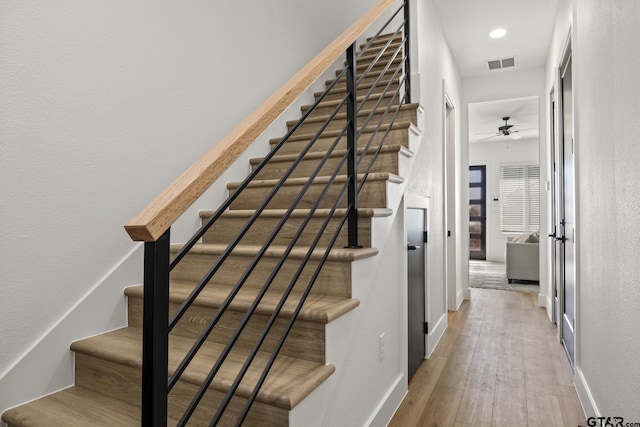 stairway featuring hardwood / wood-style flooring and ceiling fan