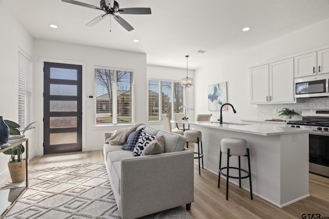 kitchen with sink, appliances with stainless steel finishes, a kitchen breakfast bar, pendant lighting, and a kitchen island with sink