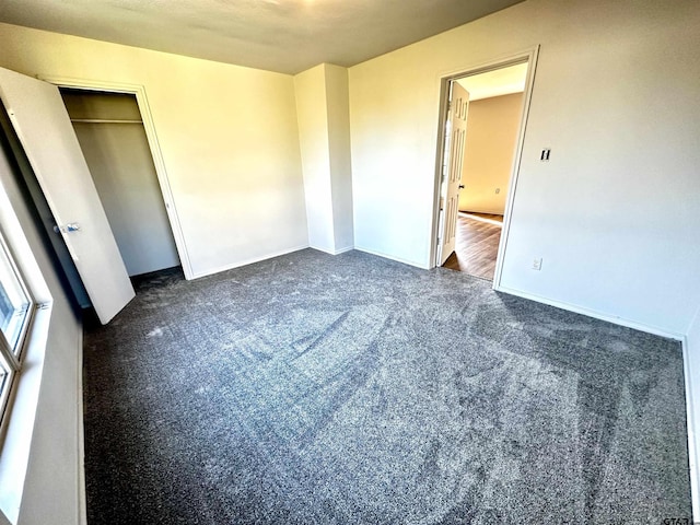 unfurnished bedroom featuring dark colored carpet and a closet