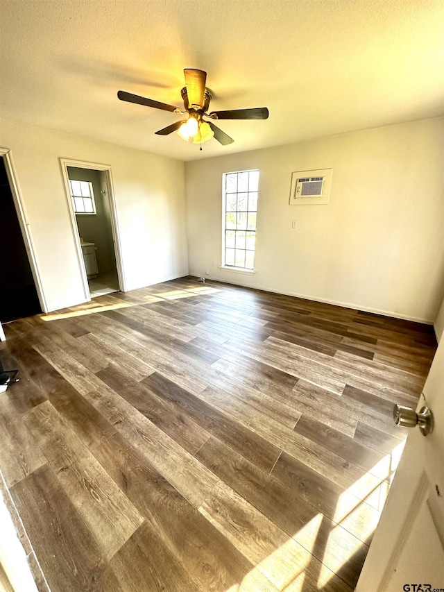 spare room with a wall unit AC, ceiling fan, hardwood / wood-style floors, and a textured ceiling