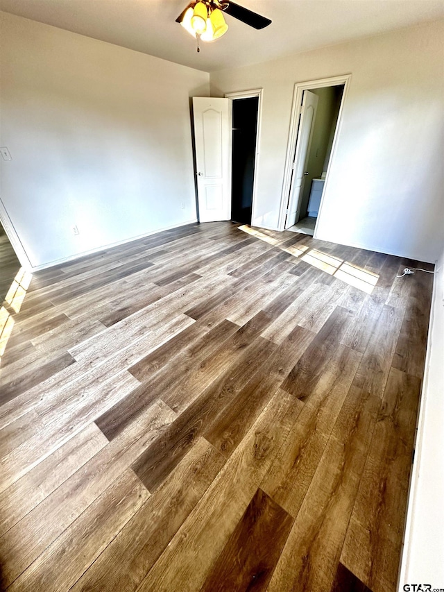 unfurnished bedroom featuring connected bathroom, a spacious closet, ceiling fan, light hardwood / wood-style flooring, and a closet