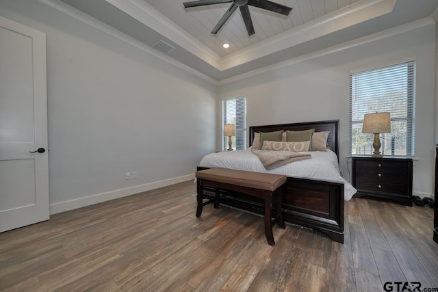 bedroom with ceiling fan, crown molding, dark hardwood / wood-style floors, and a tray ceiling