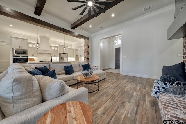 living room with wood-type flooring, ceiling fan, crown molding, and beam ceiling