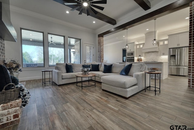 living room with ornamental molding, light wood-type flooring, ceiling fan, and beamed ceiling