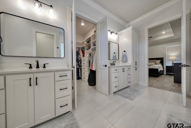 bathroom featuring a tray ceiling, crown molding, and vanity