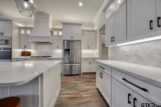 kitchen featuring custom exhaust hood, pendant lighting, backsplash, white cabinets, and appliances with stainless steel finishes