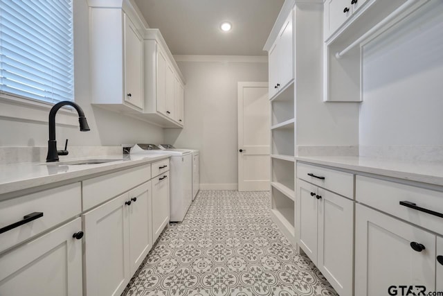 laundry room featuring sink, washer and dryer, crown molding, and cabinets