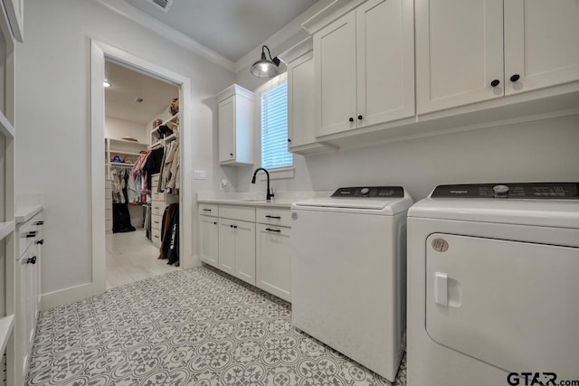 laundry room with ornamental molding, cabinets, washing machine and clothes dryer, and sink