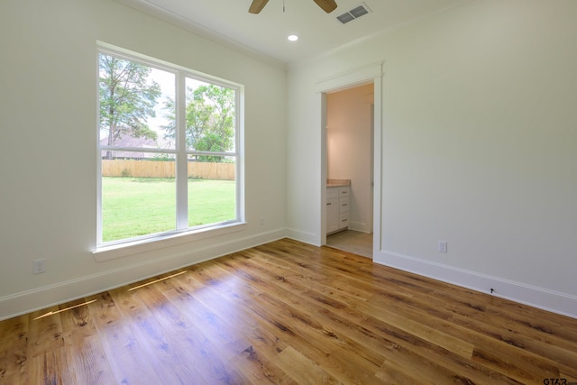 interior space featuring ceiling fan, connected bathroom, light wood-type flooring, and ornamental molding