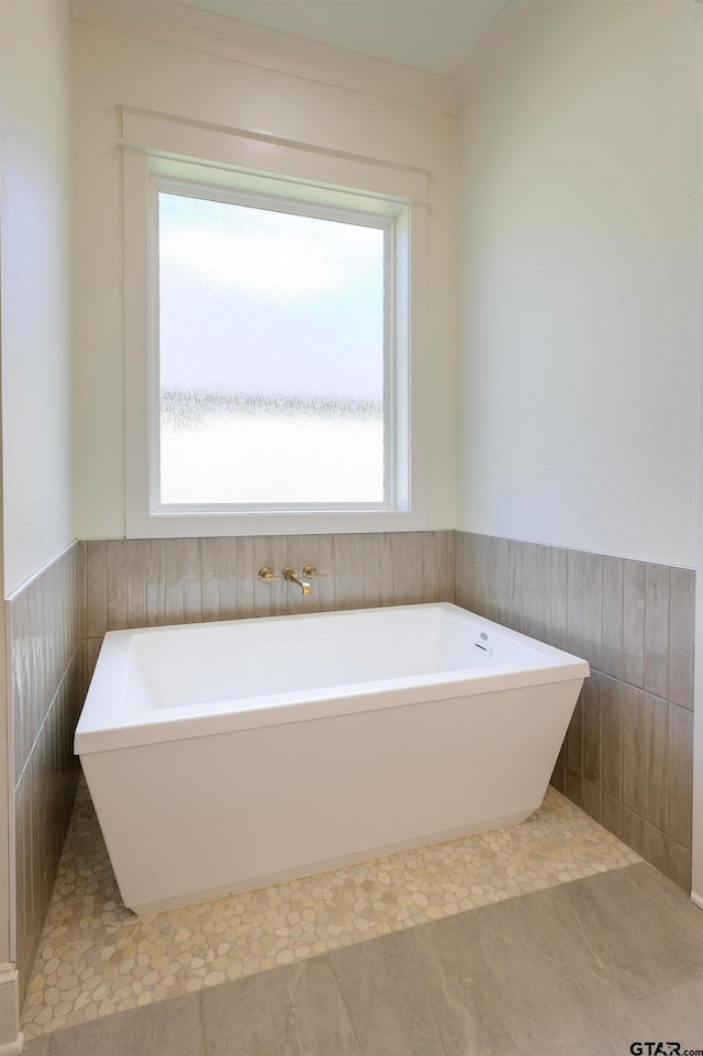 bathroom with tile walls, tile patterned flooring, and a tub to relax in