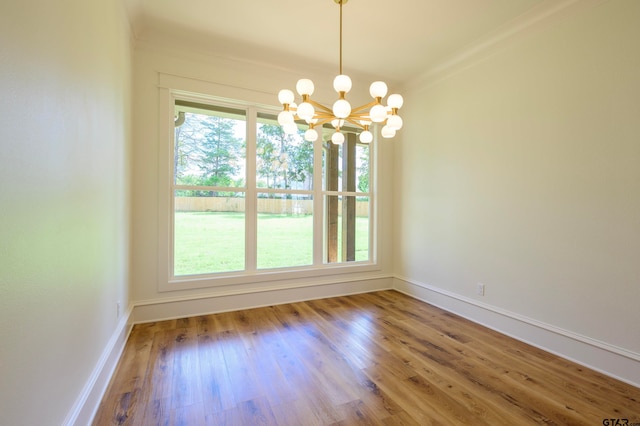 unfurnished dining area featuring an inviting chandelier, wood-type flooring, and crown molding