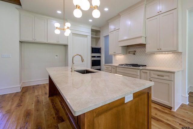 kitchen with pendant lighting, a chandelier, sink, and a kitchen island with sink