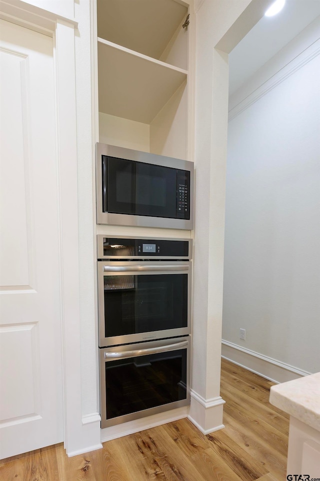 kitchen with hardwood / wood-style flooring, appliances with stainless steel finishes, and ornamental molding