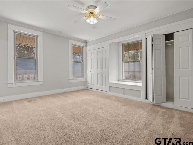 unfurnished bedroom featuring ceiling fan, two closets, and carpet floors