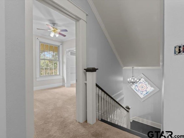 stairway featuring vaulted ceiling, ceiling fan with notable chandelier, carpet flooring, and crown molding