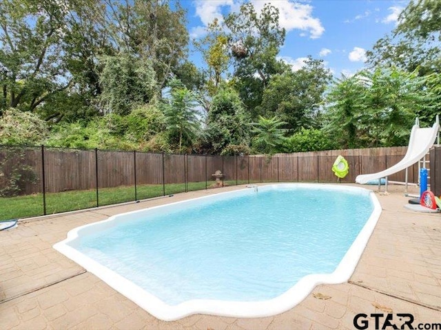 view of pool with a water slide and a patio area