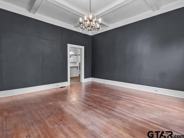 empty room featuring beamed ceiling, hardwood / wood-style floors, a notable chandelier, and crown molding