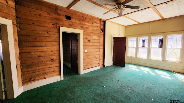 empty room with dark carpet, wooden walls, and ceiling fan