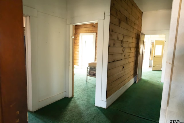 hall with dark colored carpet and wood walls