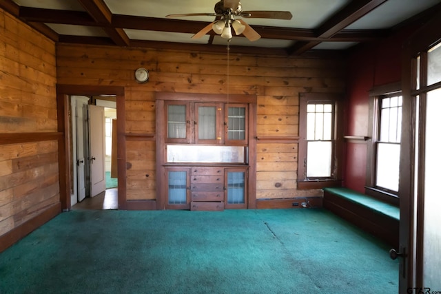 unfurnished living room with coffered ceiling, beam ceiling, and wooden walls