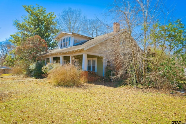 view of side of property featuring a chimney and a lawn