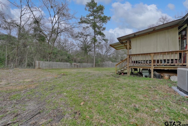 view of yard featuring fence, a wooden deck, and central AC unit