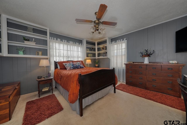 bedroom with a ceiling fan, light carpet, ornamental molding, and a textured ceiling