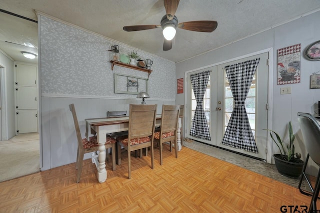 dining room featuring french doors, wainscoting, a textured ceiling, and wallpapered walls