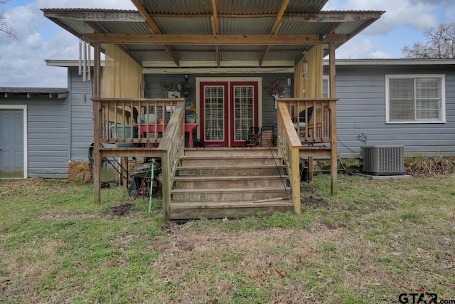 exterior space with central air condition unit, covered porch, and a yard