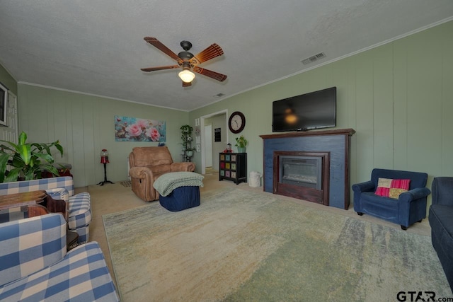 interior space featuring visible vents, ornamental molding, a ceiling fan, and a glass covered fireplace