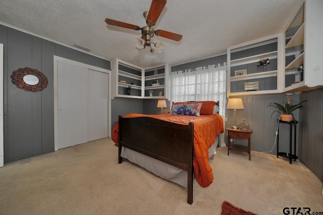 carpeted bedroom featuring a ceiling fan, visible vents, and a textured ceiling