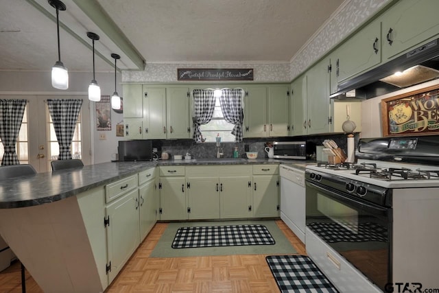 kitchen featuring gas range, a peninsula, a textured ceiling, under cabinet range hood, and a sink