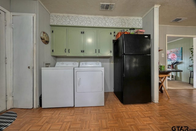 clothes washing area with visible vents, washing machine and dryer, cabinet space, and crown molding